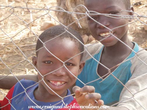 Children who don't go to school watch through the fence