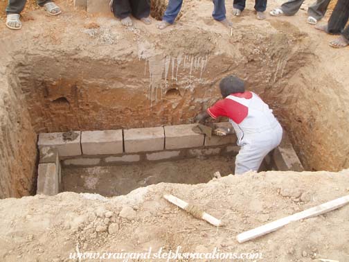 Oumar Degoga begins to lay the bricks for the water basin walls