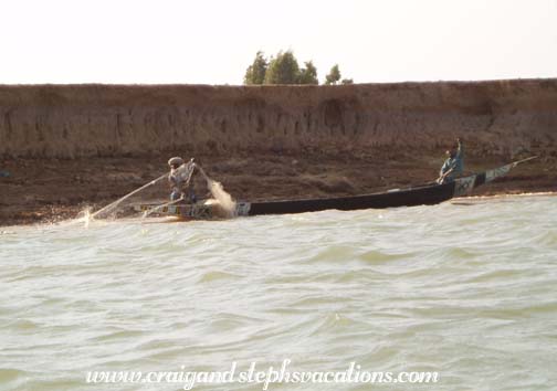 Bozo fisherman pulls a net while his son waves