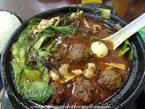 A delicious individual hot pot consisting of meatballs, quail eggs, greens, glass noodles, and delicious Middle Eastern spices