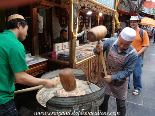 Men hammer sesame and honey into candy with wooden mallets