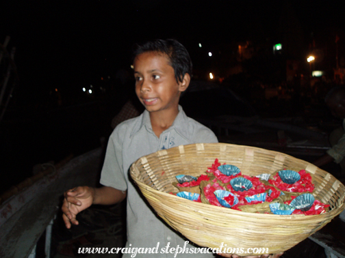 Young boy selling offerings of flowers and candles to float on the river