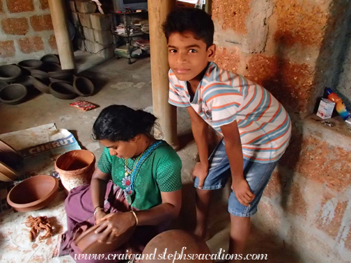 Young boy watches while his mother applies ochre to pottery, Cheruthuruthy Potter's Village
