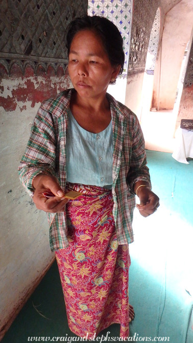 Attendant woman sells me a square of gold leaf to affix to a Buddha in a cave at Phowin Taung