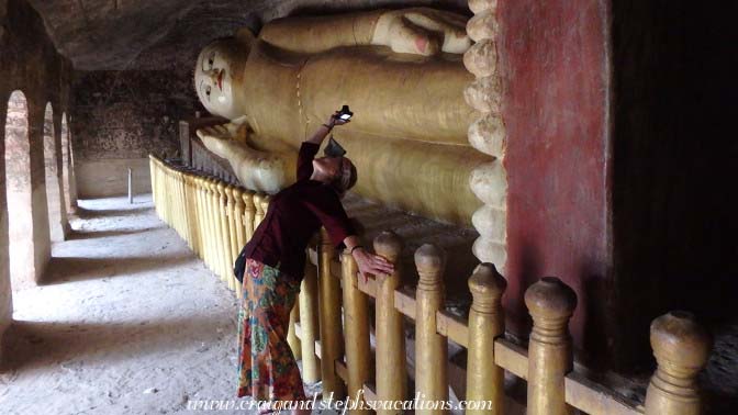 Toni stretches for the perfect angle to photograph the frescoes on the cave ceiling at Phowin Taung