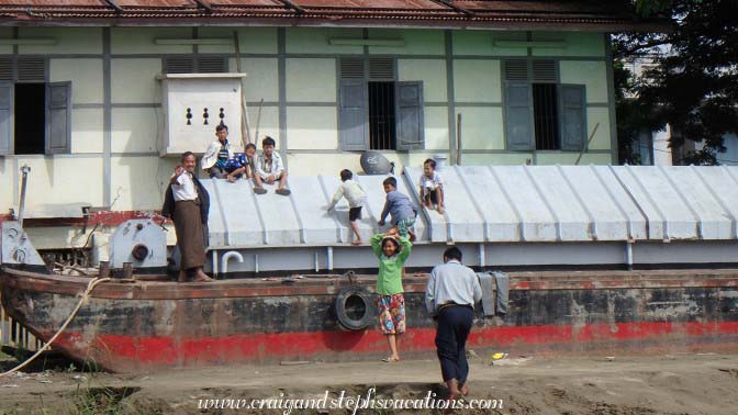 Kids slide down the roof on a neighboring boat