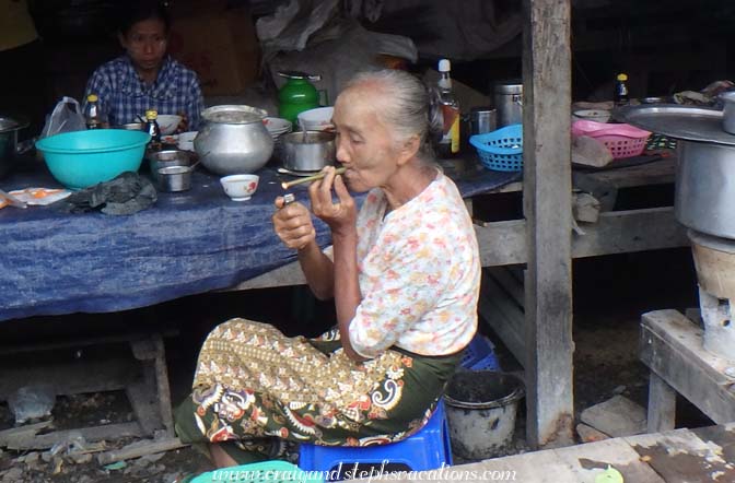 Elderly woman lights a cheroot (corn husk cigar) 