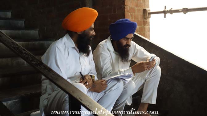 Two Sikh men sitting on the steps at the langar