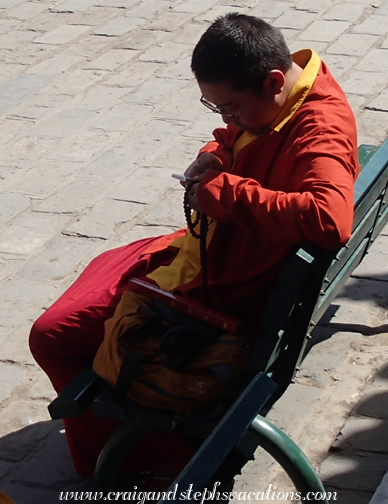 A modern Buddhist monk with prayer beads and a smartphone
