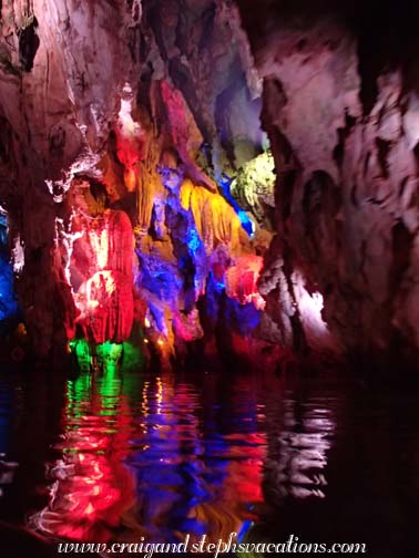 Stalactites lit up and reflecting in the water in the Dragon Palace