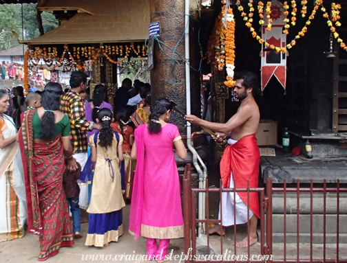 Priest blesses a woman by touching a sword to her head, Periayanampetta Bhagavathy Temple Priest blesses a woman by touching a sword to her head, Periayanampetta Bhagavathy Temple