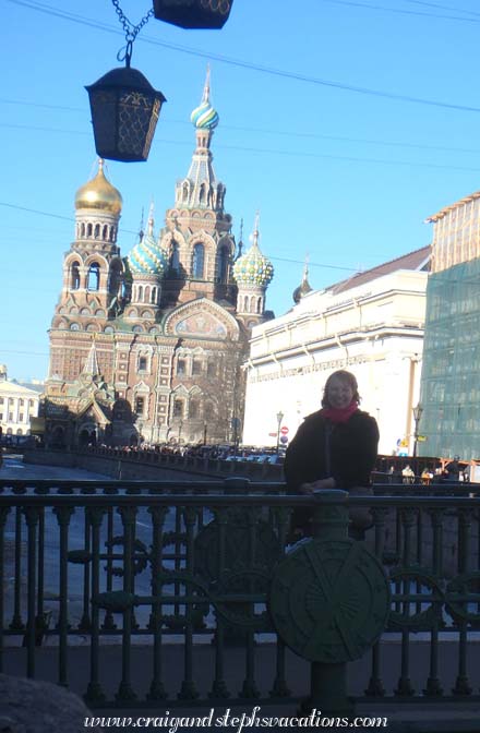 Steph on a footbridge on Griboedova Canal, with Church on Spilled Blood in the background